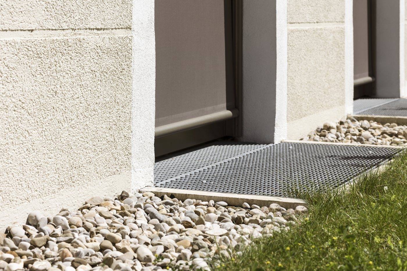 A gravel drainage strip along the base of a house wall